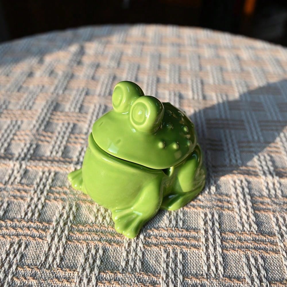 Add a touch of whimsy to your home or office with this unique and asymmetrical ceramic ashtray featuring a playful frog design. With its lid, it not only provides a functional way to dispose of ash and debris, but also acts as a decorative piece. Made with expert craftsmanship, this ashtray is sure to impress.