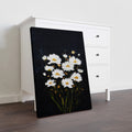 White daisies bloom against a striking black canvas, creating a sophisticated contrast that elevates any interior space. This wall art piece combines botanical elegance with modern minimalism, making it an ideal focal point for living rooms, bedroom walls, or above sofas. The crisp white florals draw the eye while the dark background grounds the composition, adding depth and visual interest without overwhelming your décor.