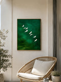 Framed emerald green bird poster with white flying birds above wicker chair
